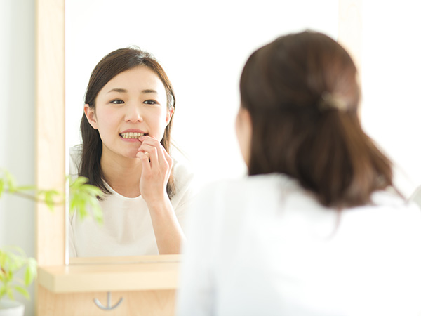 鏡で歯茎を見る女性